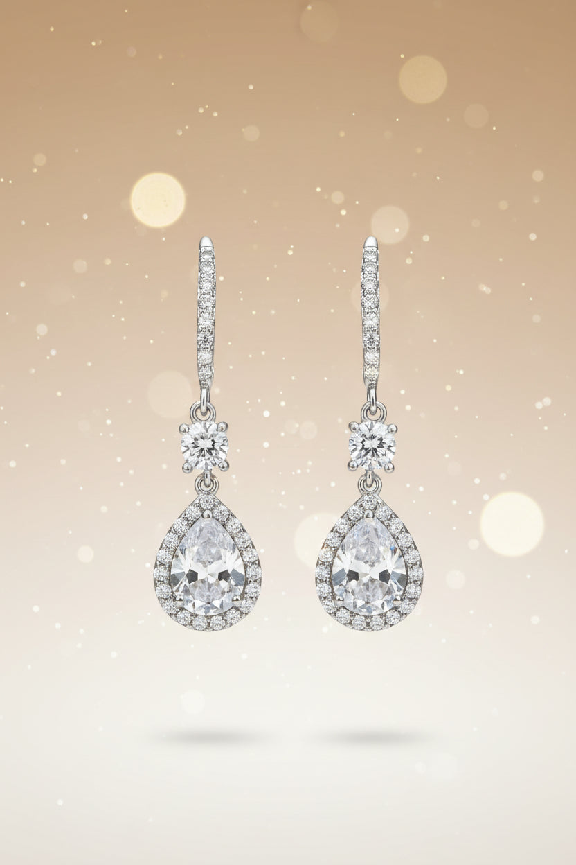 Pair of silver teardrop earrings with clear gemstones on a light gray background