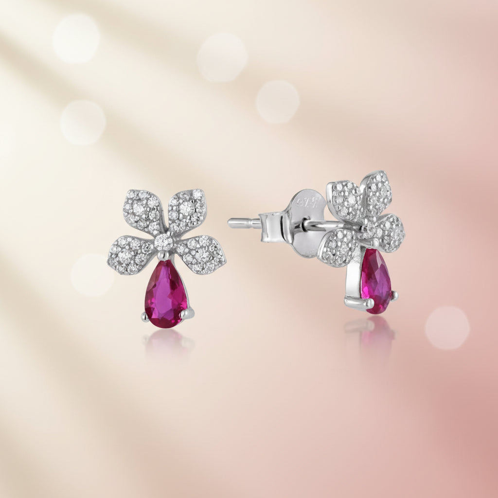 Silver floral earrings with red gemstones on a white background